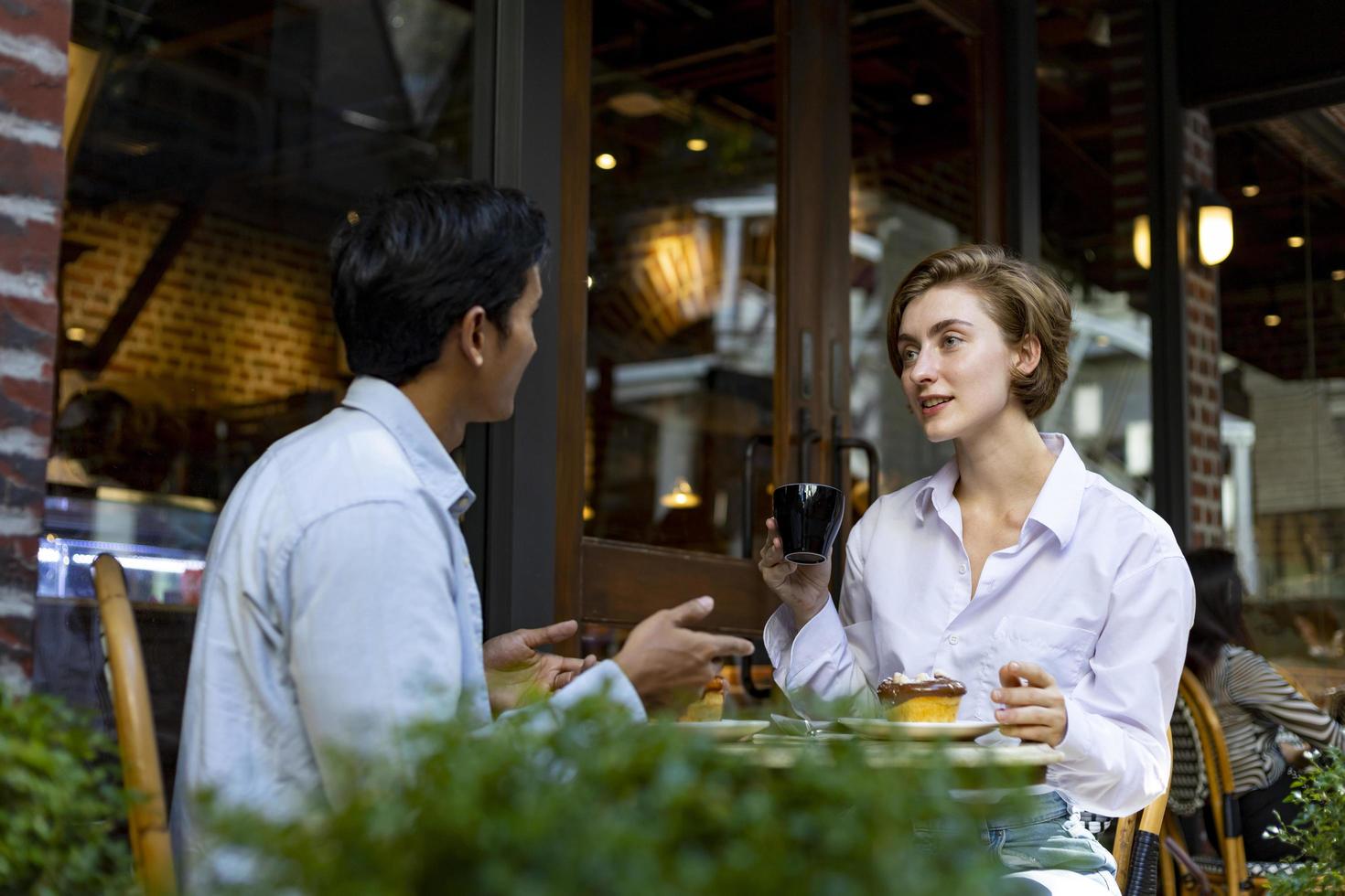 una pareja tiene una cita en un café bistró de estilo europeo disfrutando del ambiente matutino alrededor de la plaza de la ciudad con pasteles dulces y una taza de café foto