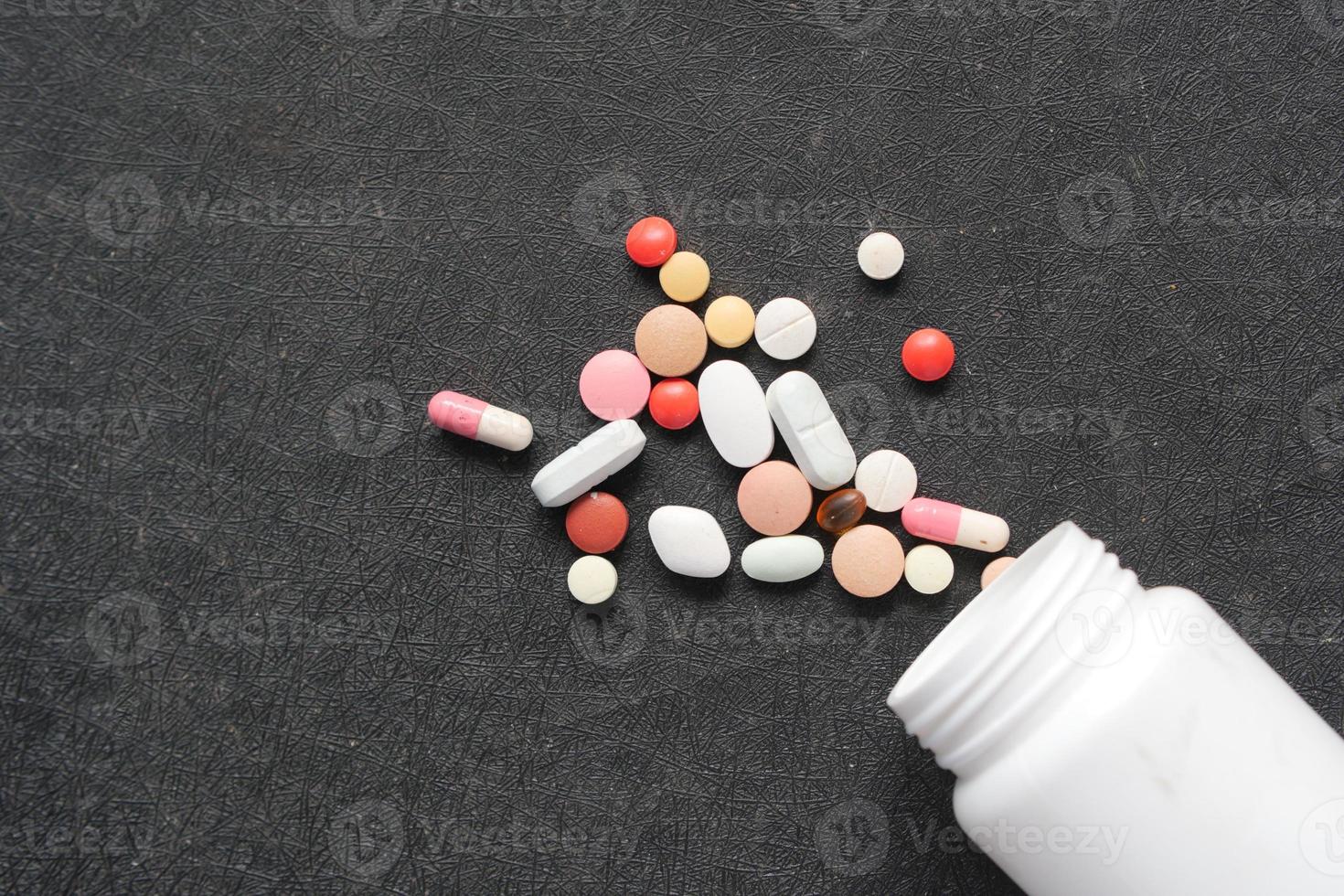 Close up of many colorful pills and capsules on black background photo