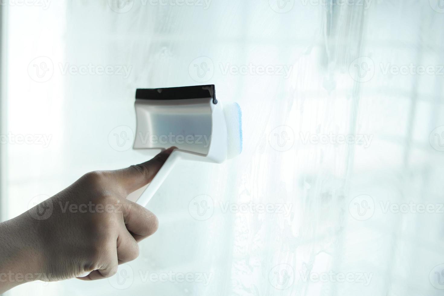 person hand cleaning window glass with brush photo