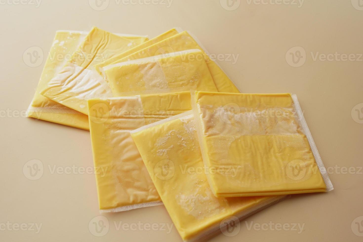 Transparent packet with slices of cheese on yellow , photo