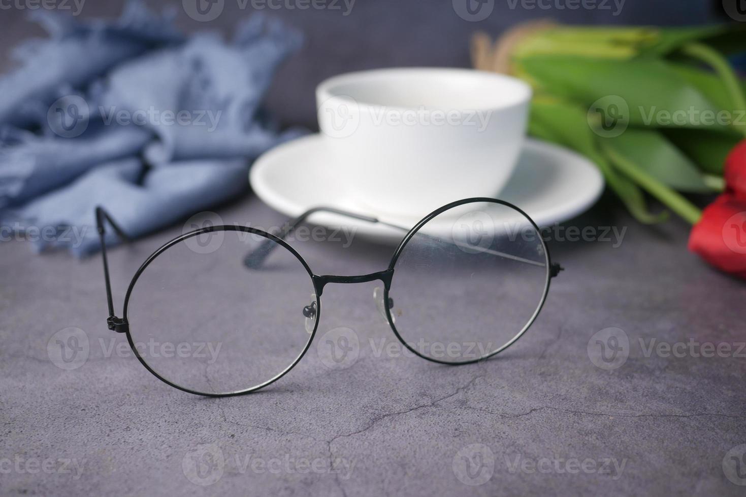 coffee, tulip flower and eyeglass on black background . photo