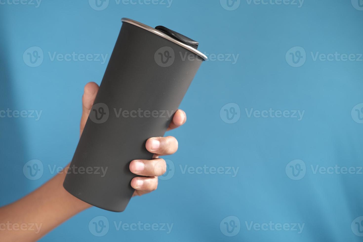 holding reusable eco coffee cup on blue background photo