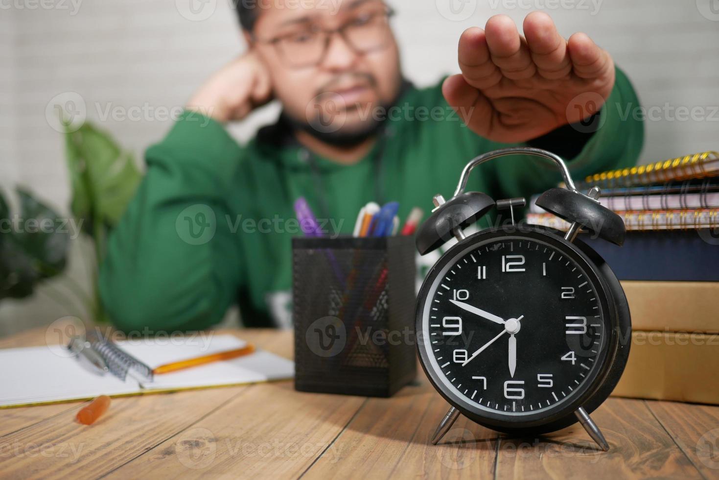 frustrated bot stopping his alarm clock while studying photo