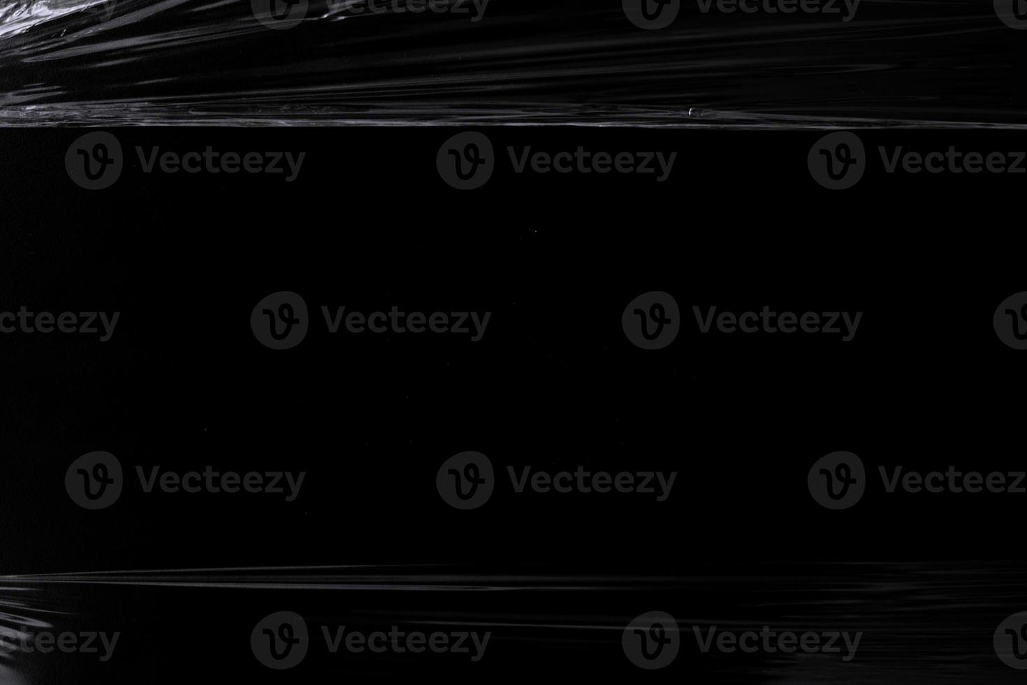 a black transparent plastic texture with hole for poster and cover art. realistic plastic wrap for overlay, copy space and photo effect. wrinkled plastic surface on black background