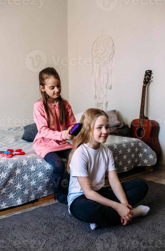 Two girls schoolgirl friends play at home, do their hairstyle photo