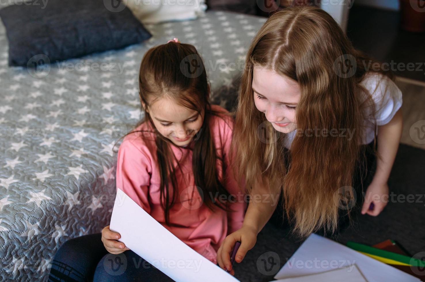 Two girls friends play at home, draw with pencils and felt-tip pens and have fun photo