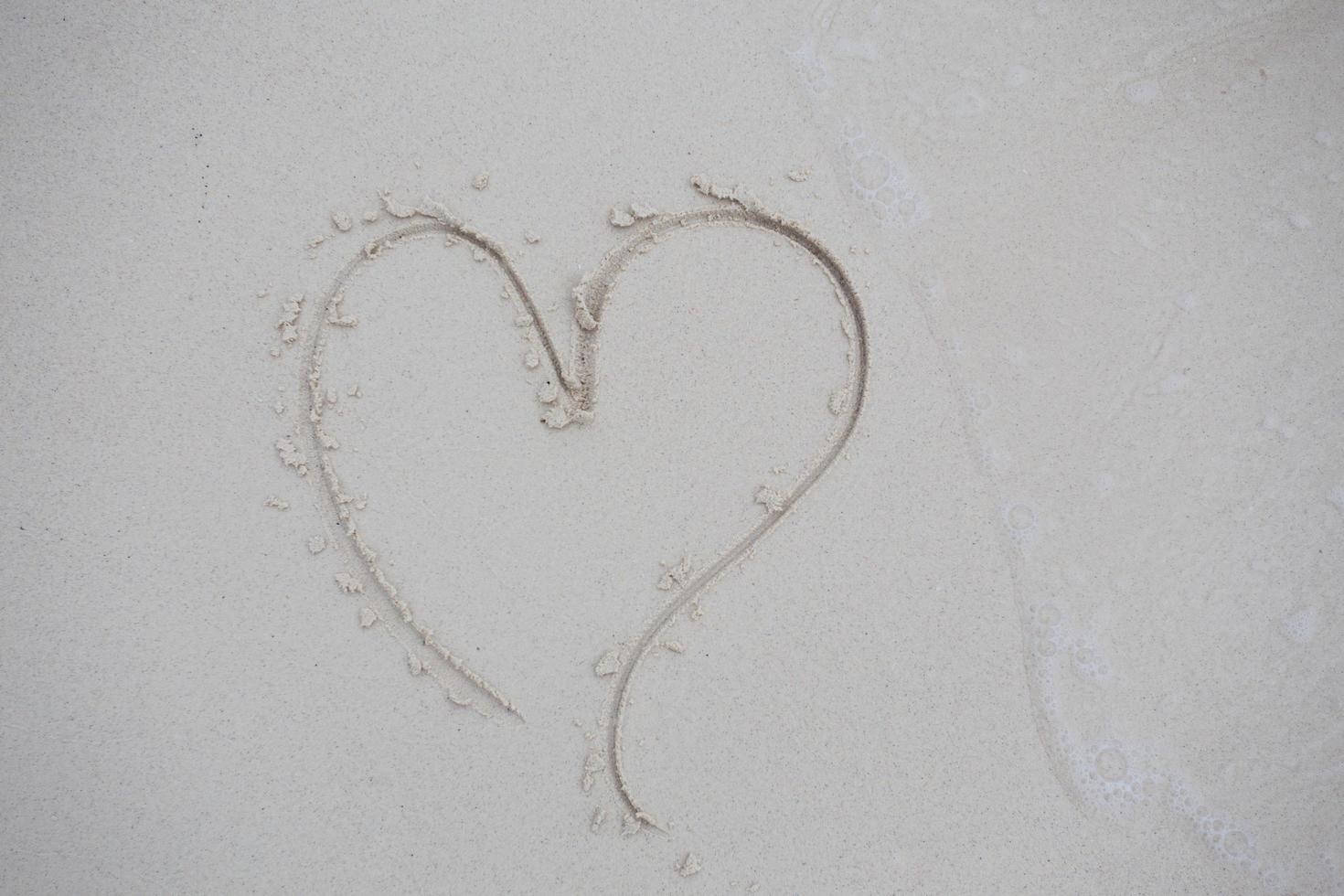 corazones dibujados en la arena de una playa foto