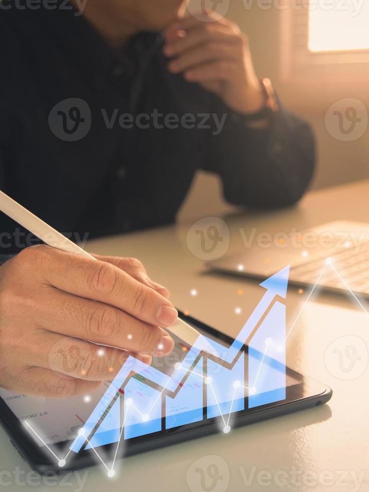 businessman working with statistics, looking at laptop and phone screens with graphs and diagrams, synchronizing electronic devices, checking financial report presentation, sitting at desk photo
