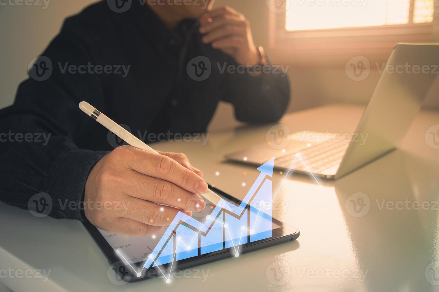 businessman working with statistics, looking at laptop and phone screens with graphs and diagrams, synchronizing electronic devices, checking financial report presentation, sitting at desk photo