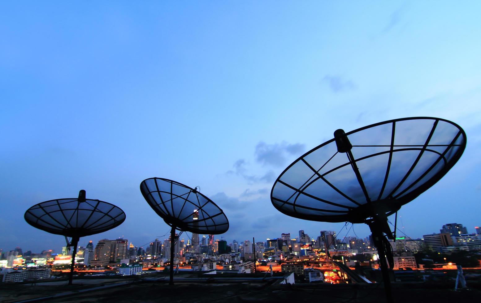 black antenna communication satellite dish over sunset sky in cityscape photo