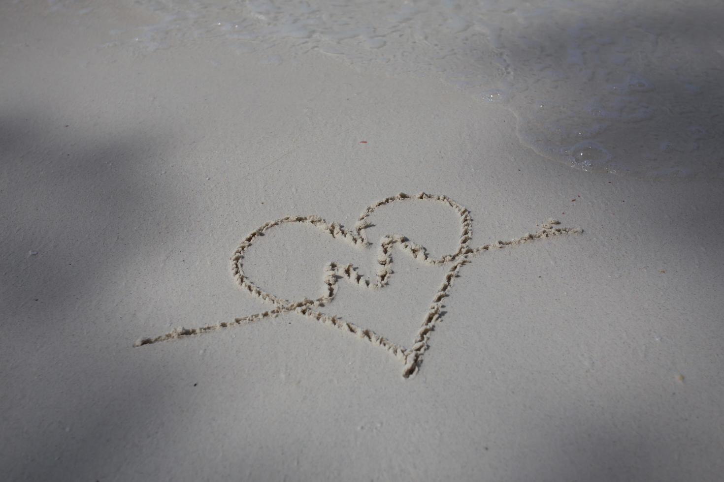 corazones dibujados en la arena de una playa foto