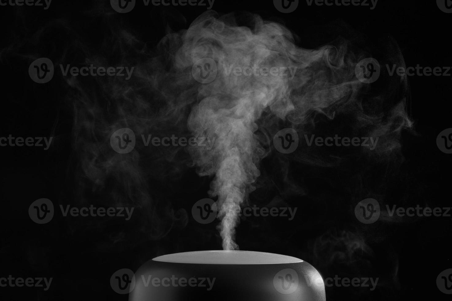 Modern air humidifier on black background. White steam close-up. The concept of humidification of the air. Photo with copy space.