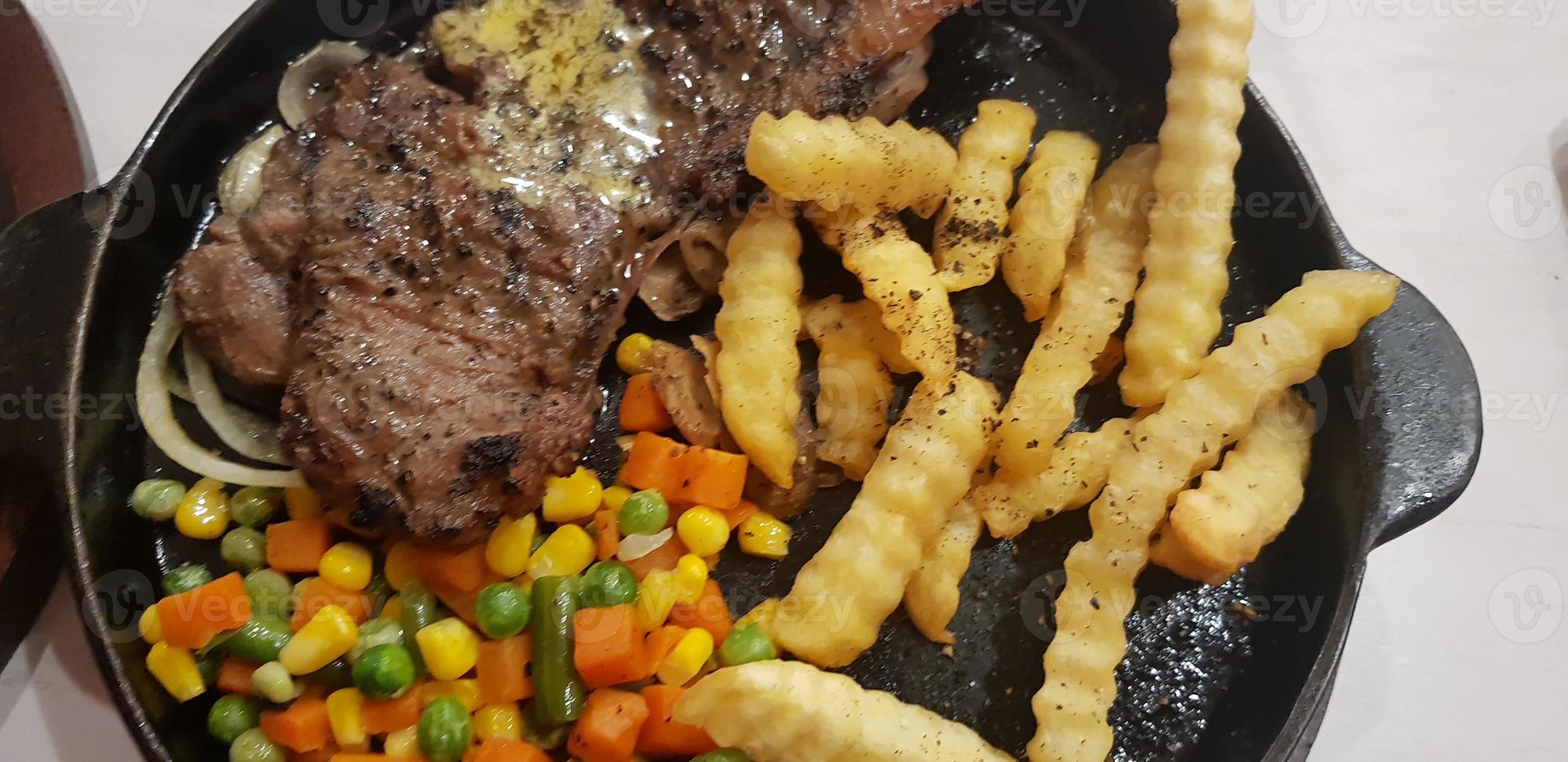 The best food in the world beef steak along with fried potatoes with delicious mushroom sauce and salad plated in beautiful black stripes plate photo