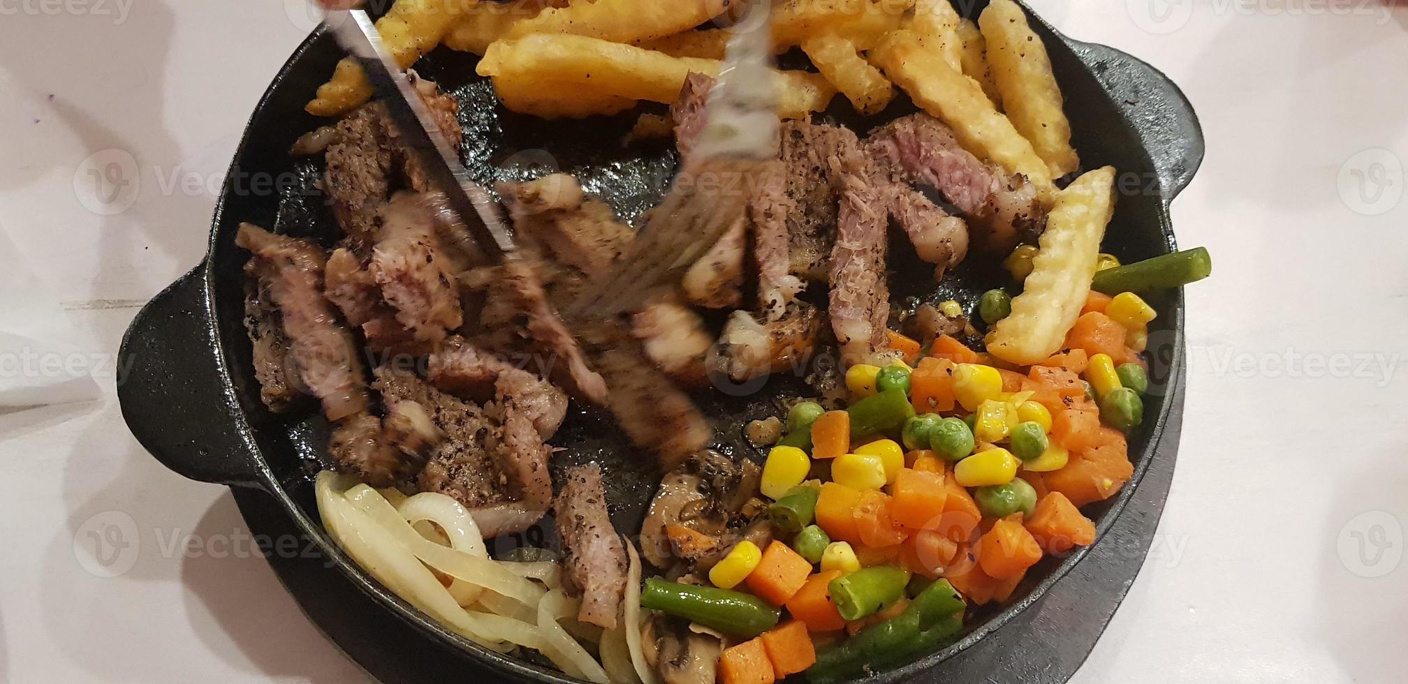 The best food in the world beef steak along with fried potatoes with delicious mushroom sauce and salad plated in beautiful black stripes plate photo