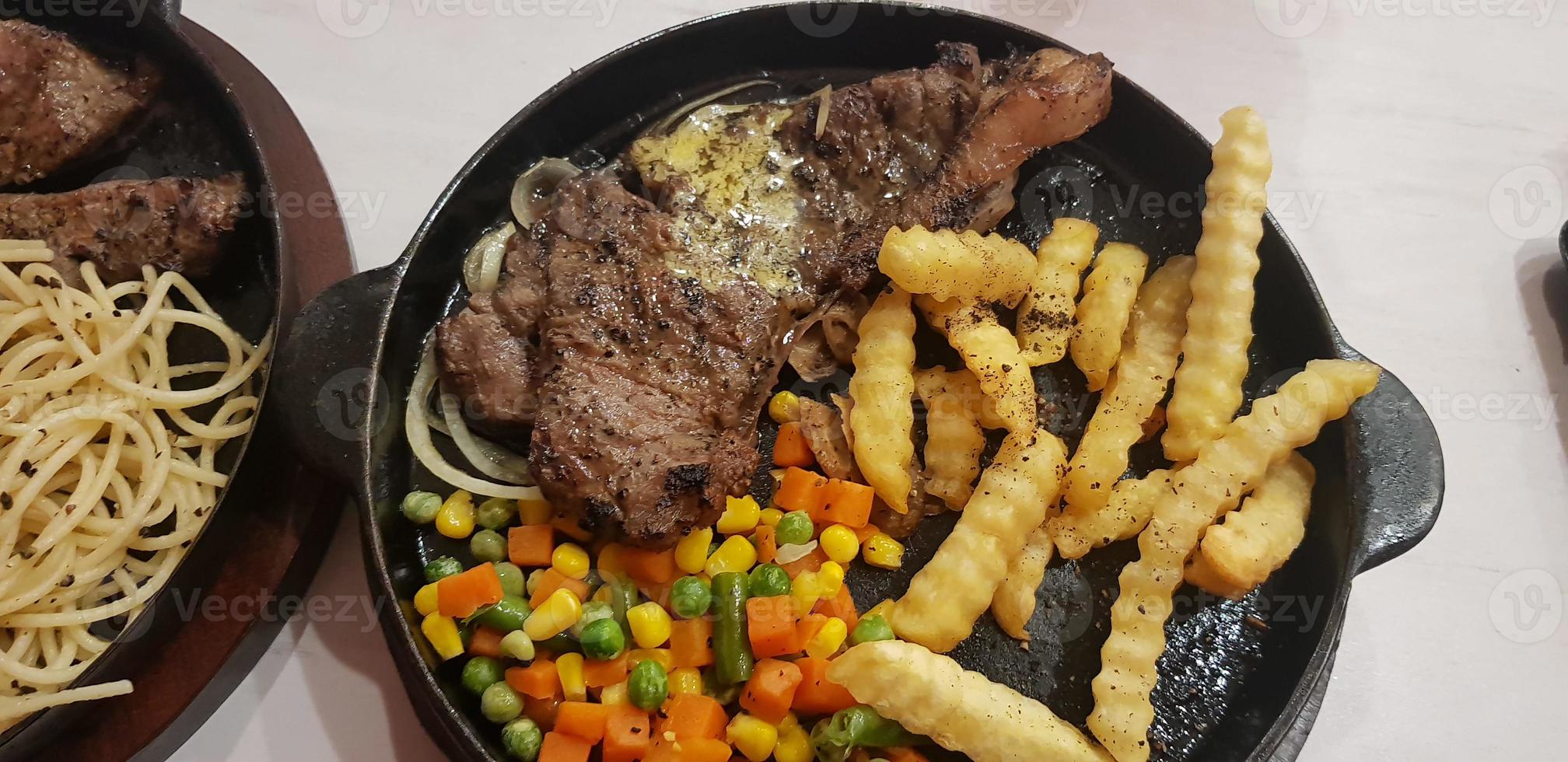 The best food in the world beef steak along with fried potatoes with delicious mushroom sauce and salad plated in beautiful black stripes plate photo