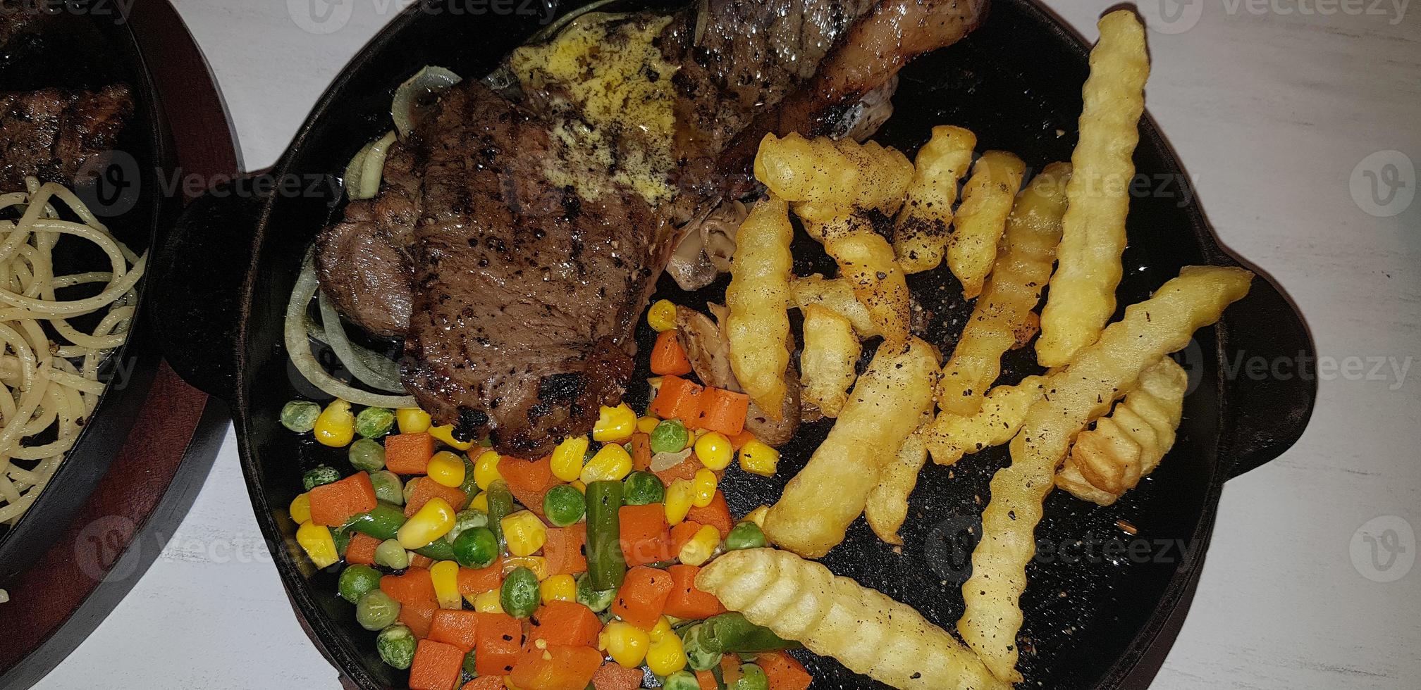 The best food in the world beef steak along with fried potatoes with delicious mushroom sauce and salad plated in beautiful black stripes plate photo