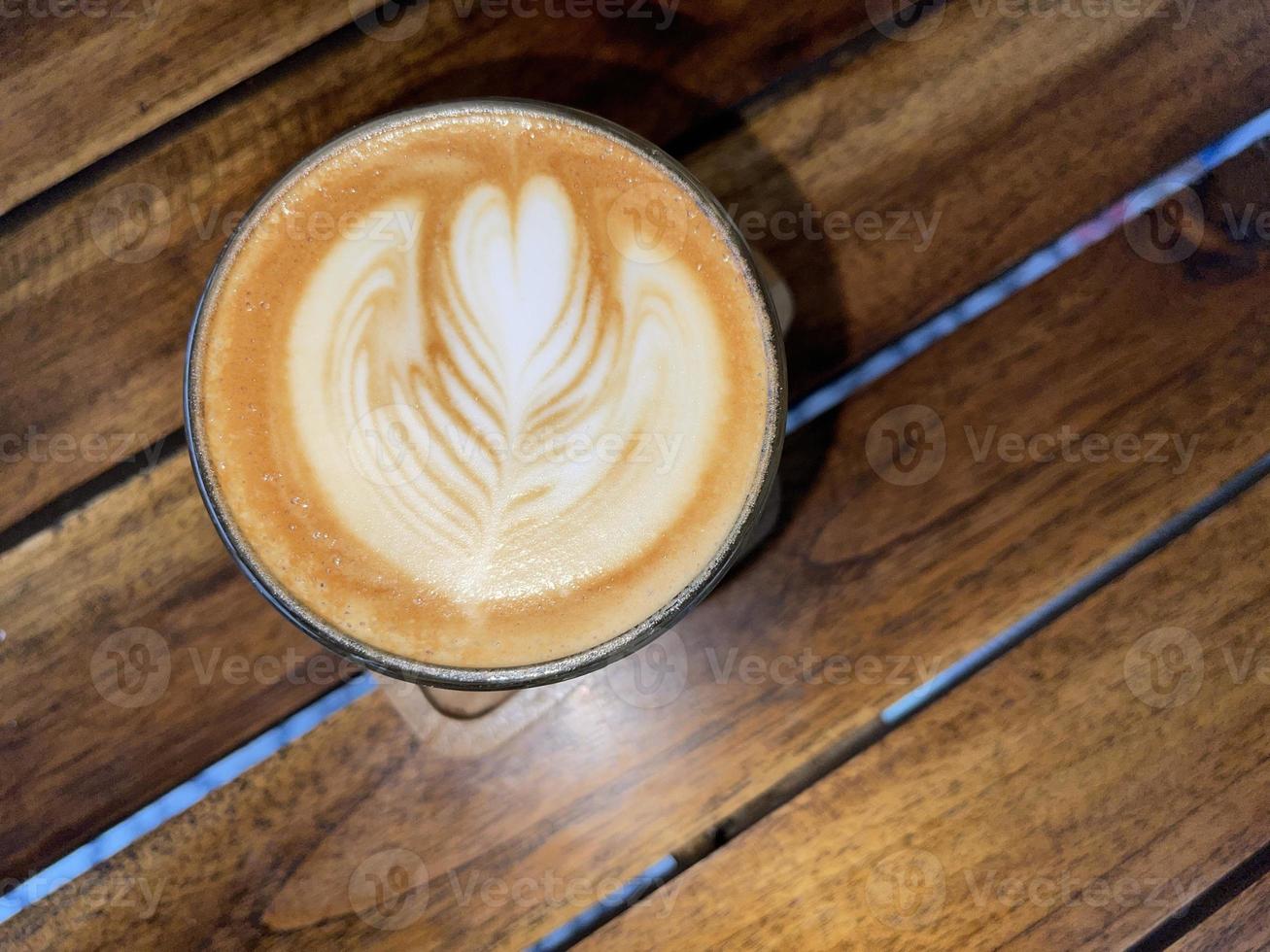 beautiful cup of cappuccino coffee with latte art in the wooden space background photo