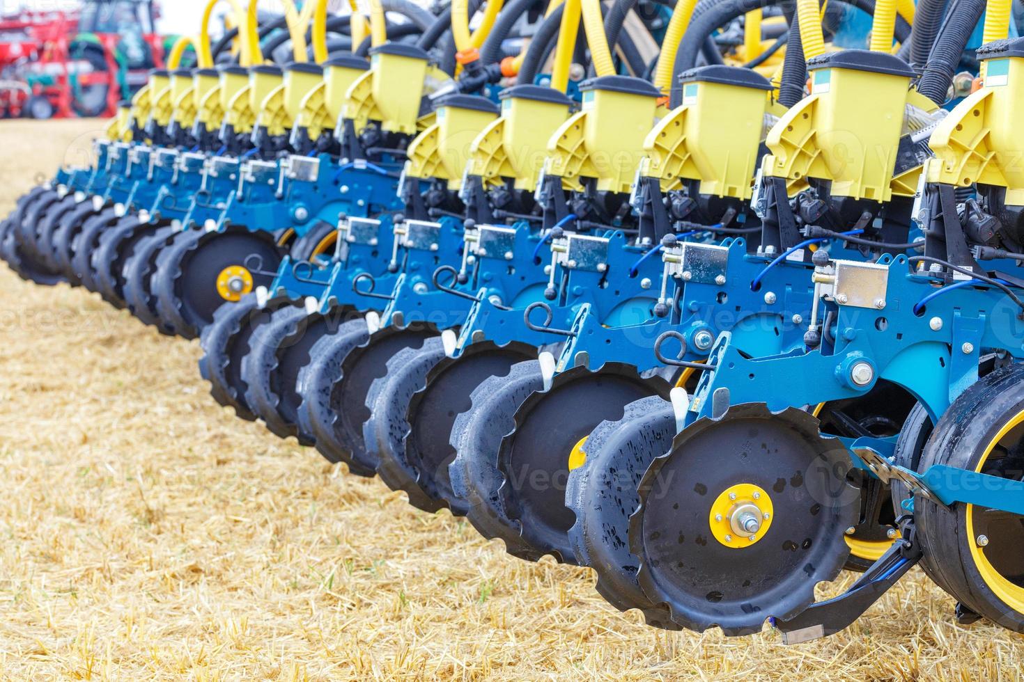 A row of wheels with a pneumatic distribution mechanism and pipes on a multi-row planter against the backdrop of an agricultural field. photo