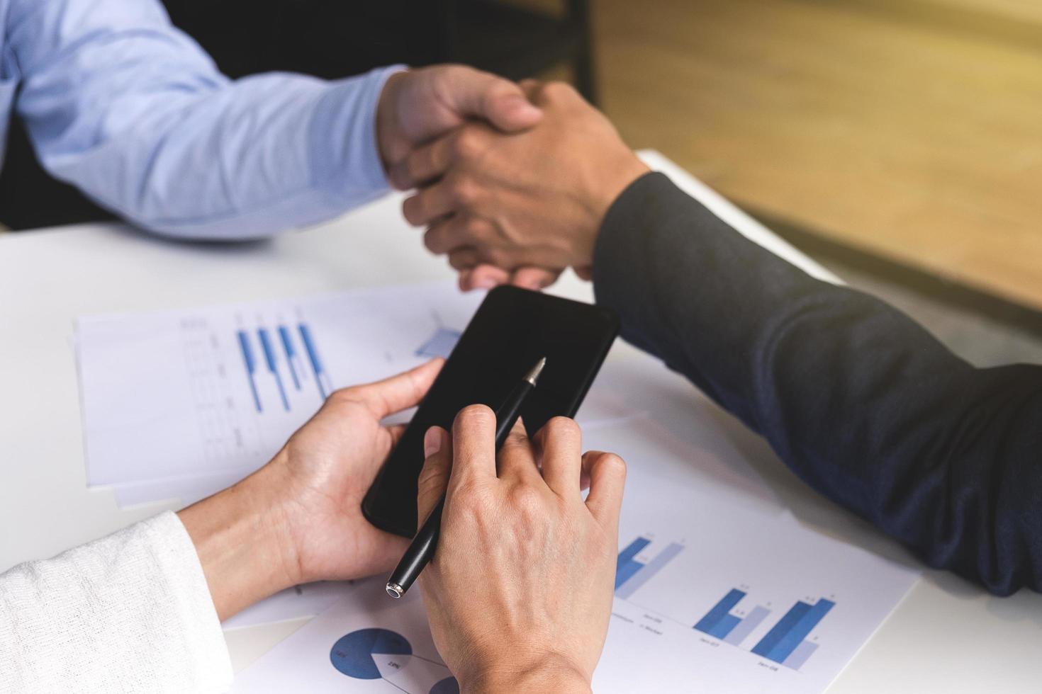 Teamwork process, Close-up of two business people shaking hands while sitting at the working place. photo