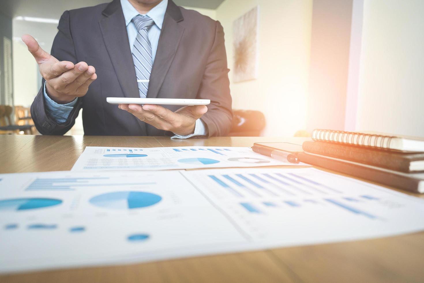 Handsome young businessman working with touchpad while sitting on the couch in office and financial statistic graph. photo