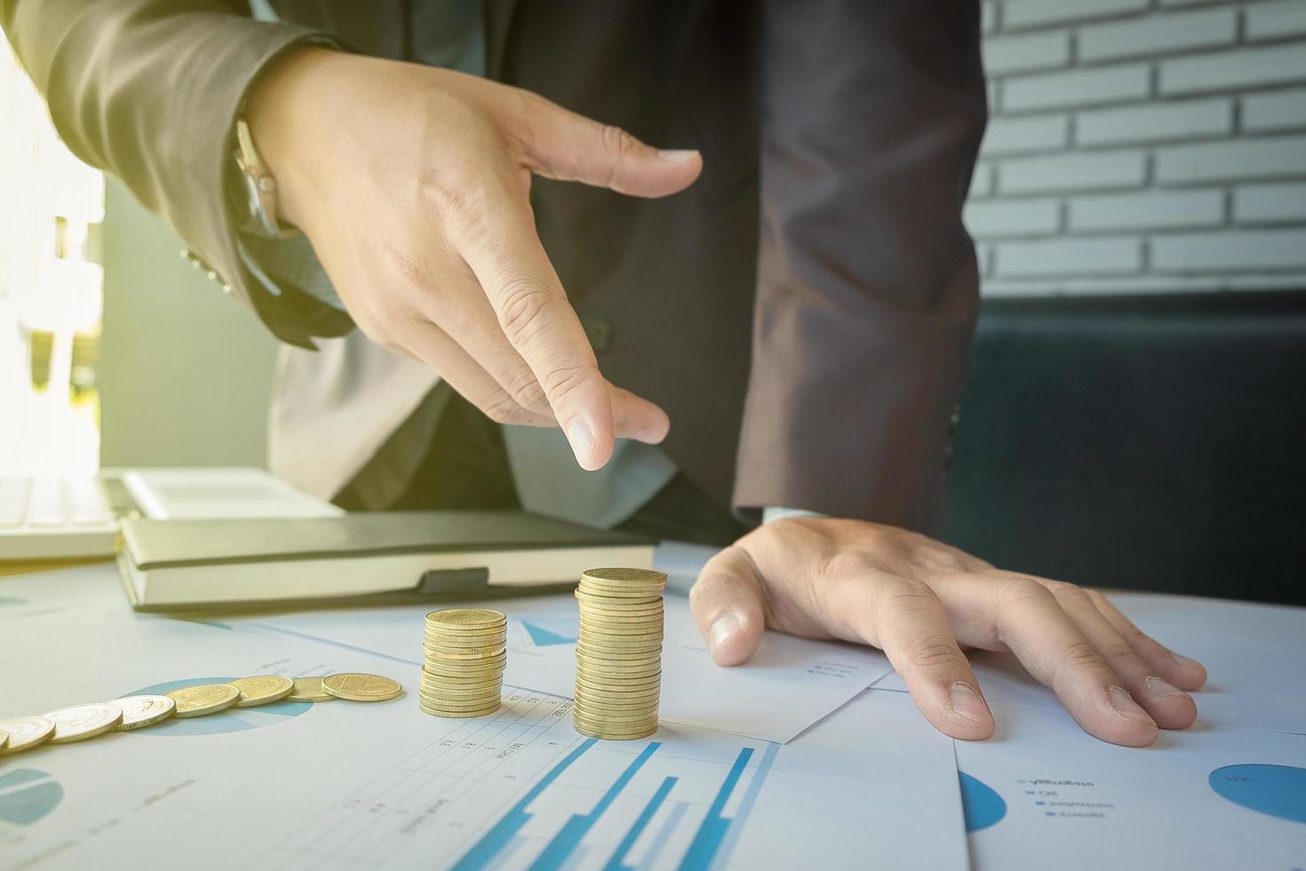 Close-up of Businessman pointing coin to rising stack of coins. photo