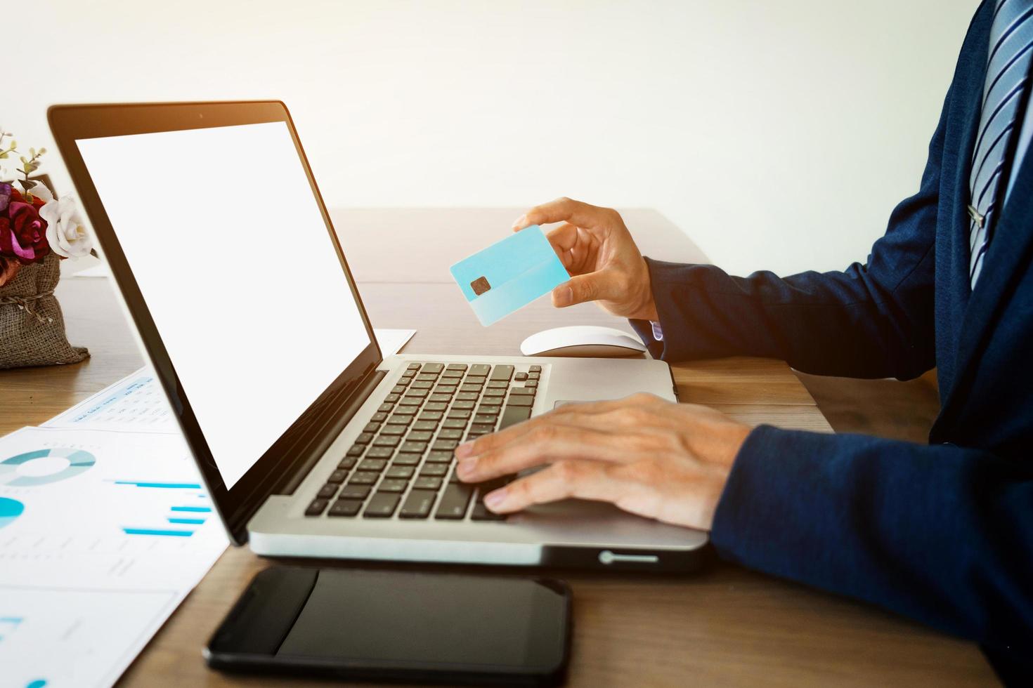 Close-up of man hands holding business card, working on laptop and smart phone in cafe with internet. photo