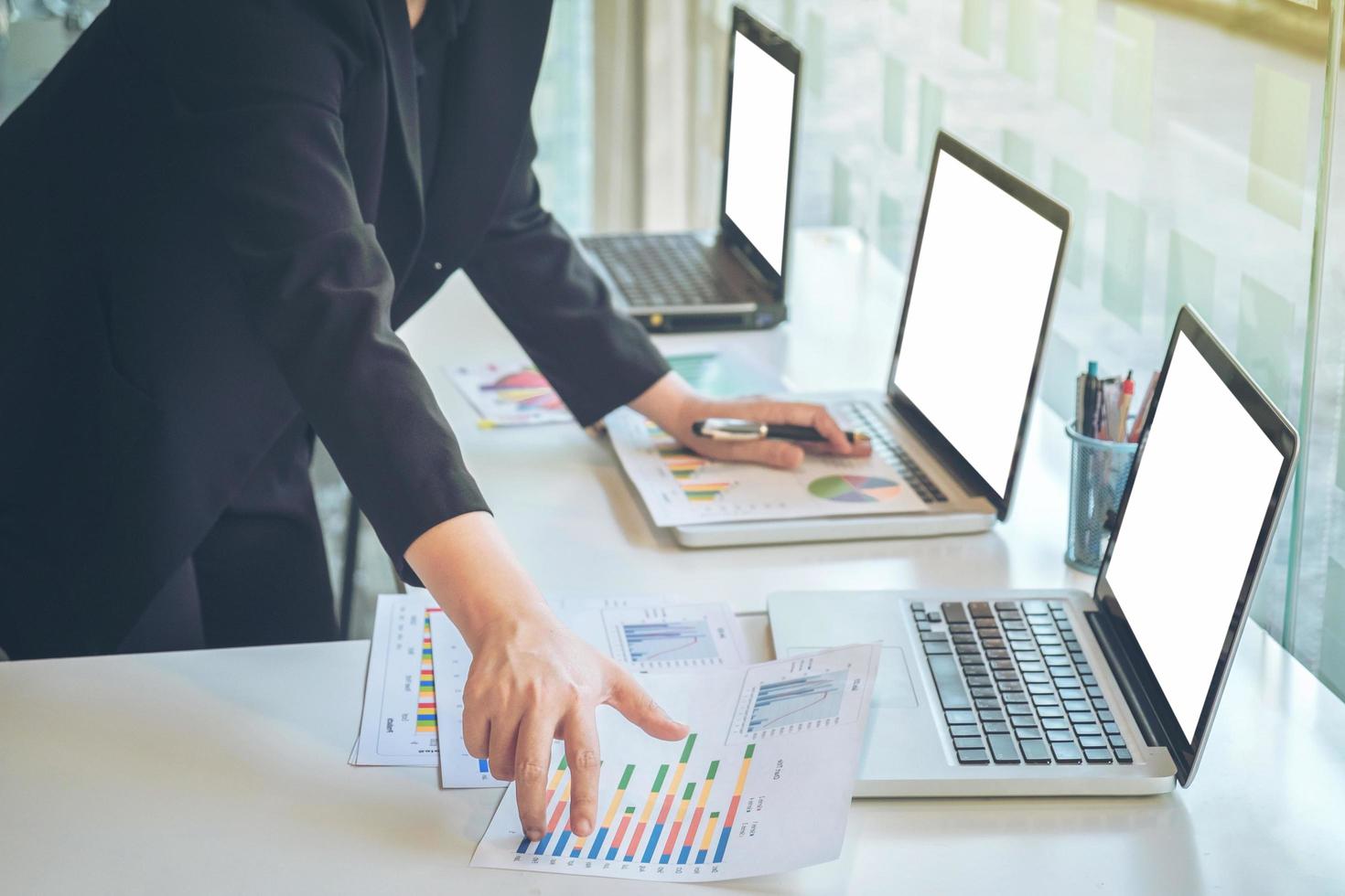 businesswoman using laptop at office desk and many document data graph in morning light, business concept. photo