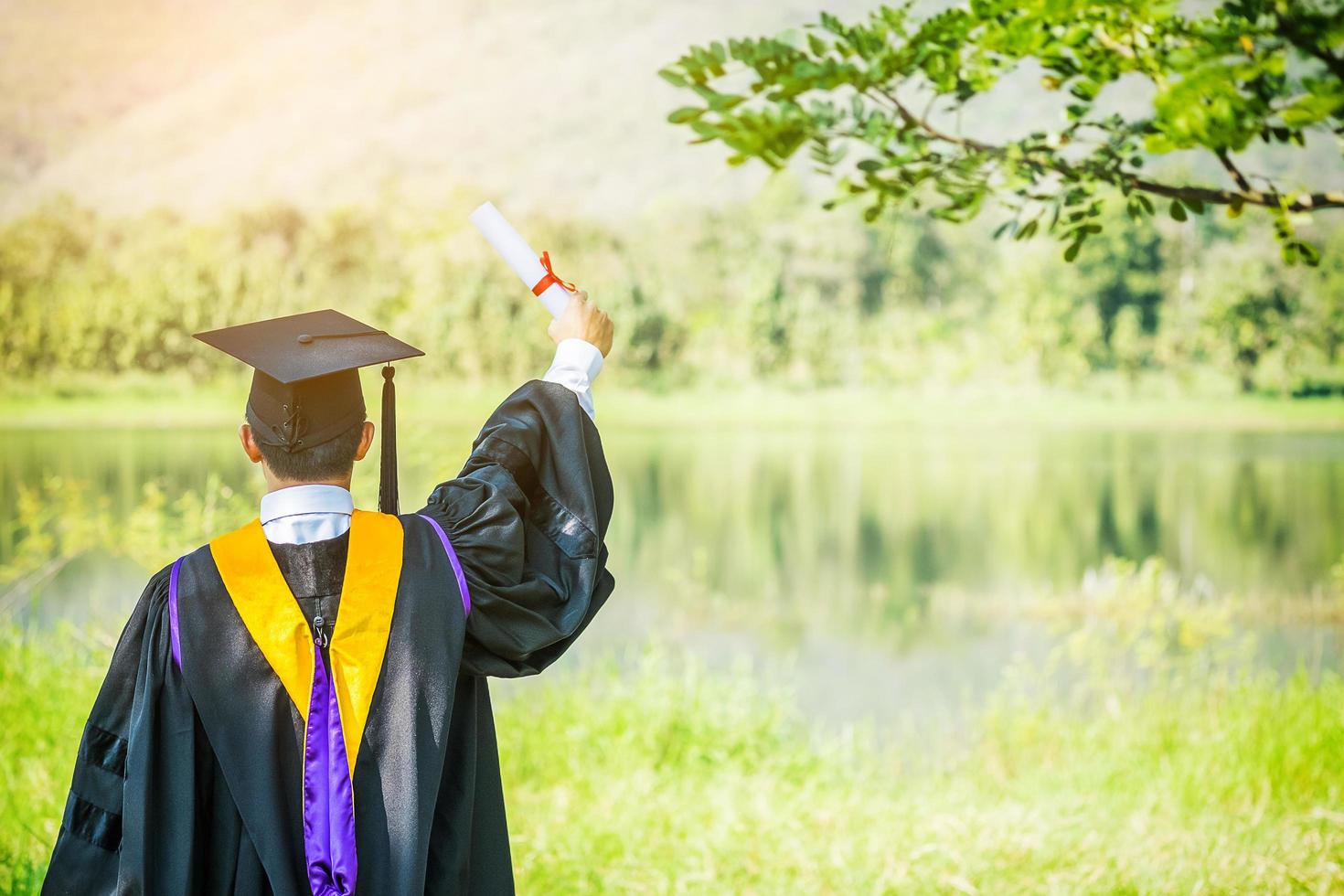 Graduate put he hands up and celebrating with certificate in he hand and feeling so happiness in Commencement day. photo