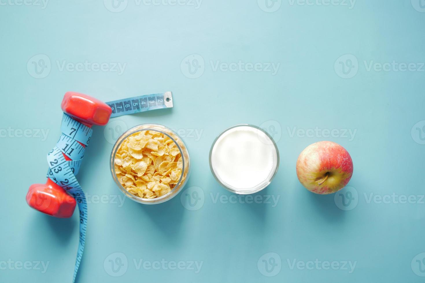 top view of cereal, apple and dumbbell on blue background photo