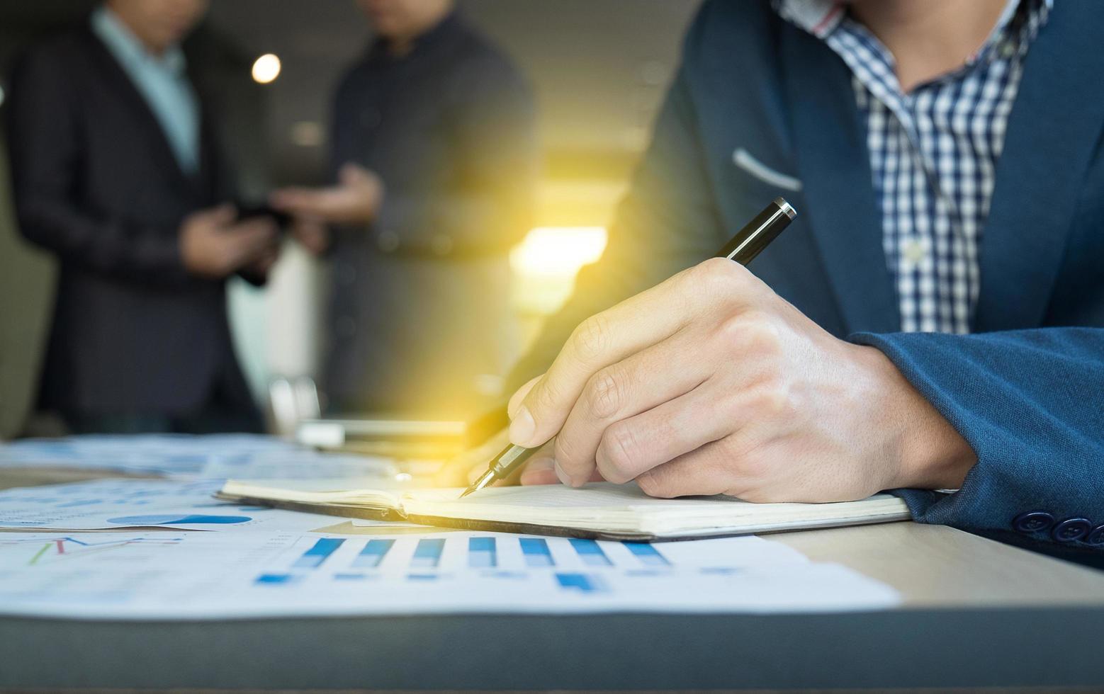Close up of business man hand writing on notebook paper with business strategy diagram on wooden desk in office, teamwork process. photo