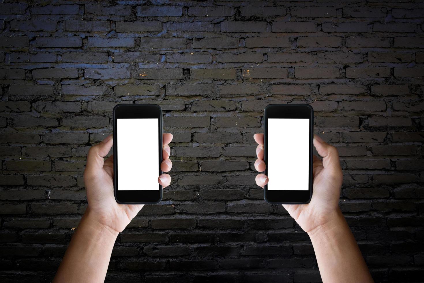 Man's hands holding blank screen of a smartphone at the old black brick wall. photo