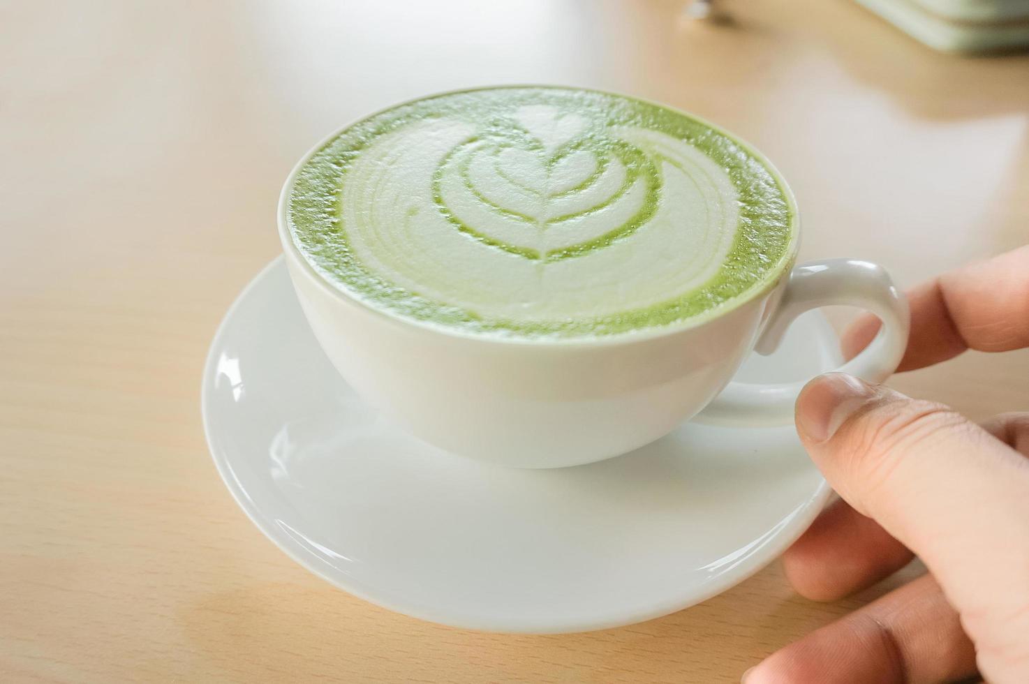 a man's hand holding a hot matcha green tea cup photo