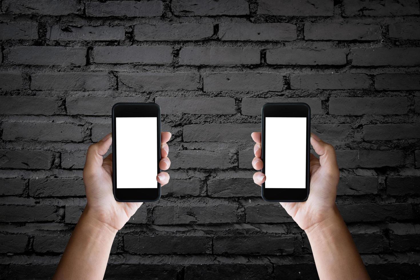 Man's hands holding blank screen of a smartphone at the old black brick wall. photo