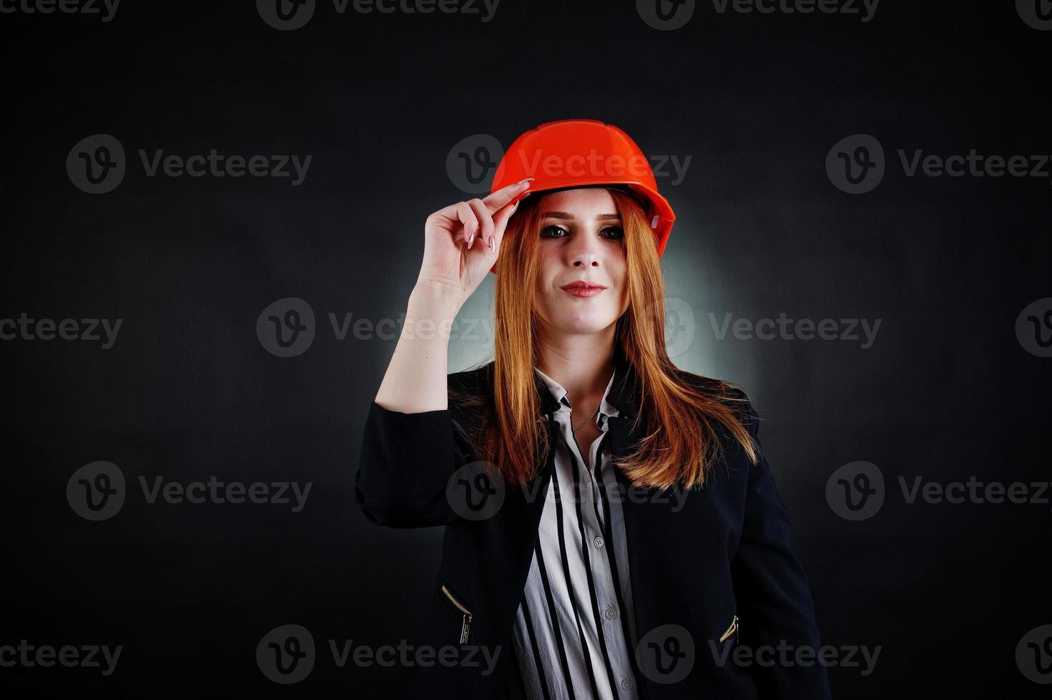 mujer ingeniera en casco de protección naranja sobre fondo negro de estudio. foto