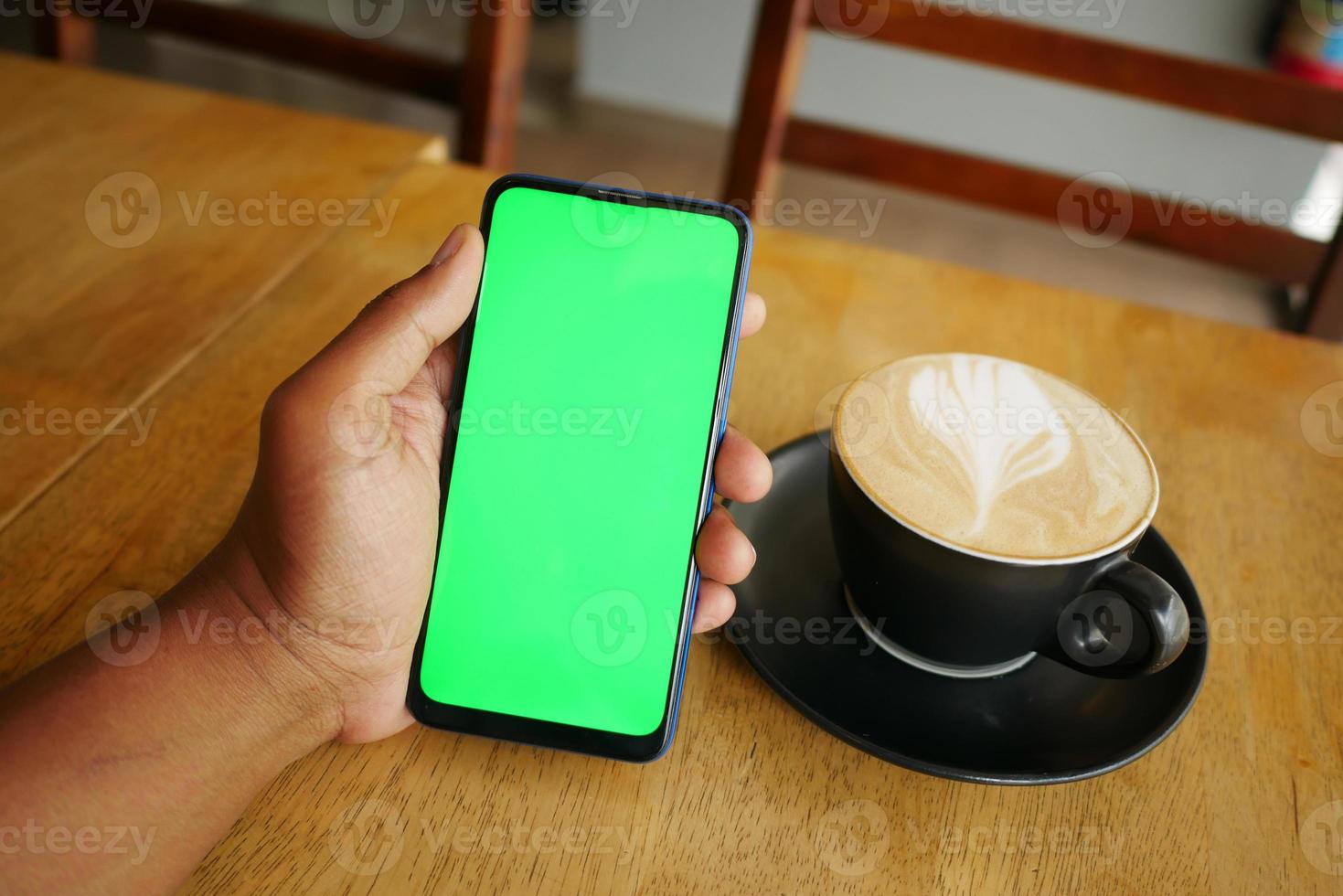 holding a cpu of coffee and using smart phone with green screen photo