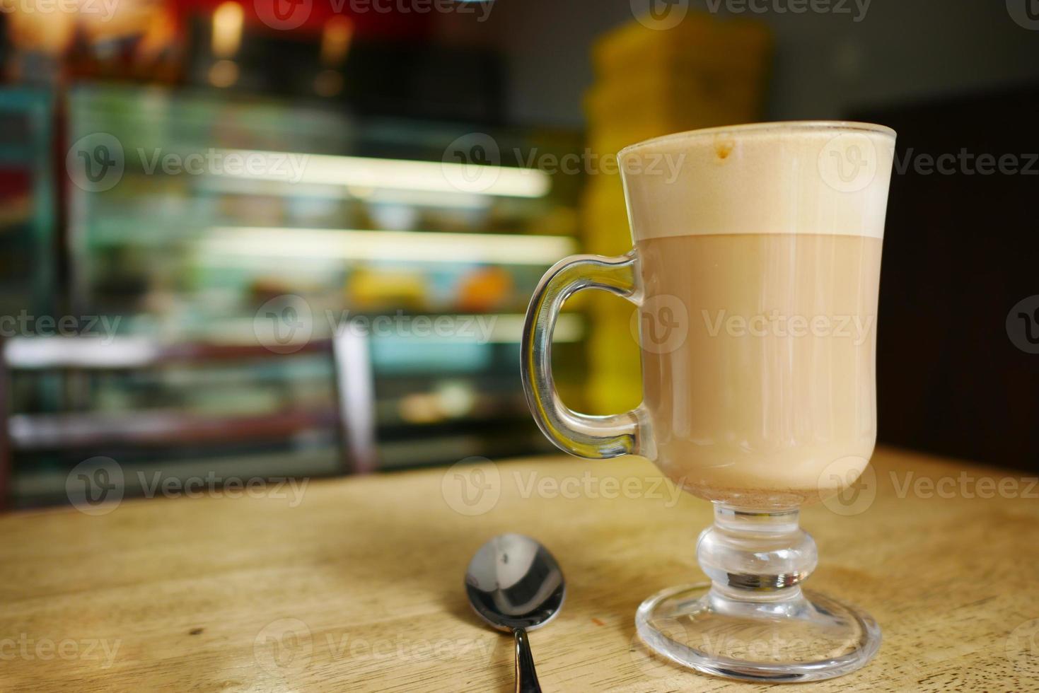 a cup of late coffee and spoon on cafe table photo