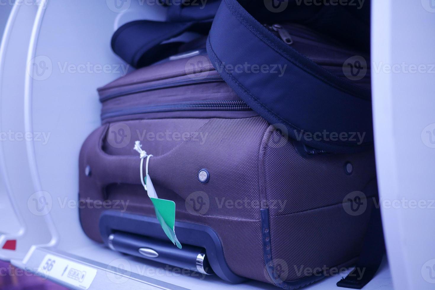 suitcase in a overhead baggage area in a Airplane cabin photo