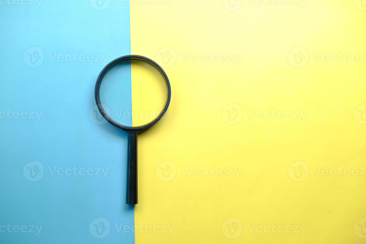 a magnifying glass on color background top view photo