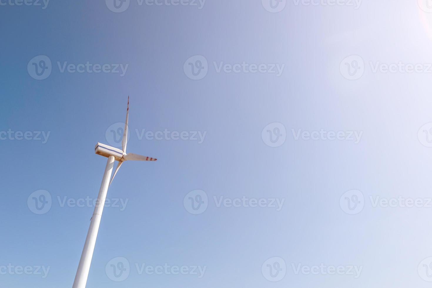 rotating blades of a windmill propeller on blue sky background. Wind power generation. Pure green energy. photo