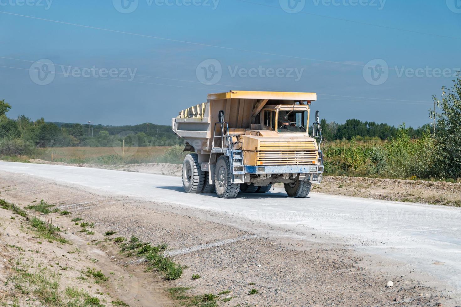 large dump truck loaded with rocks drive on dust road. Mining industry. Heavy equipment. photo