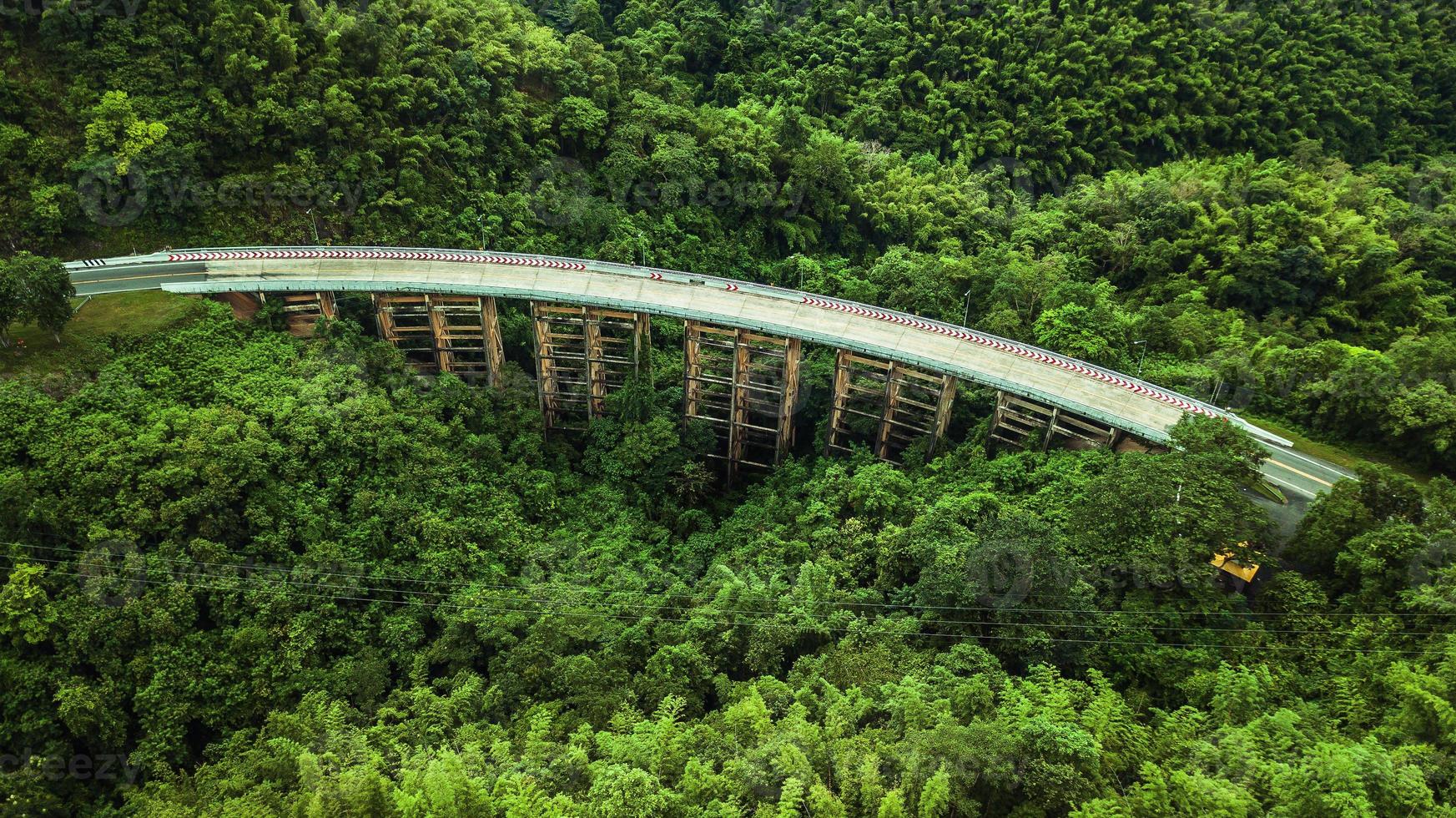 An aerial view of  Road or bridge is in the middle of a forest photo