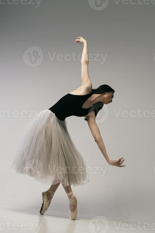 ballerina in a bodysuit and a white skirt improvises classical and modern choreography in a photo studio