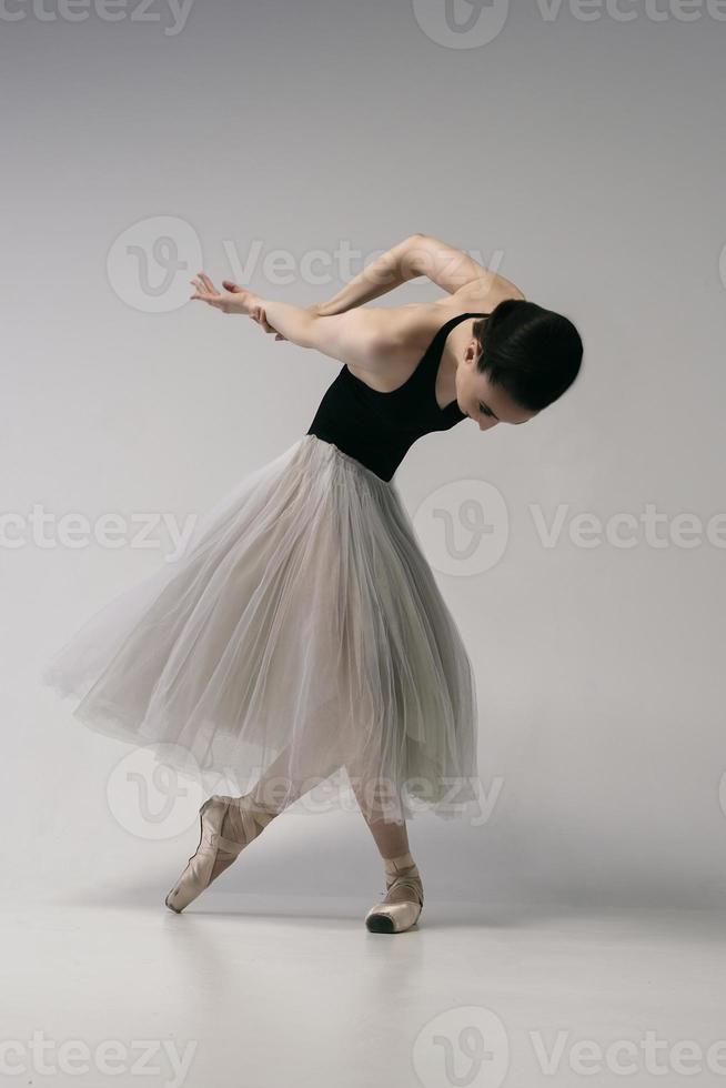 ballerina in a bodysuit and a white skirt improvises classical and modern choreography in a photo studio