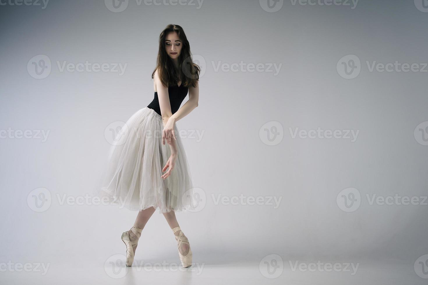 a ballerina in a bodysuit and a white skirt improvises classical and modern choreography in a photo studio