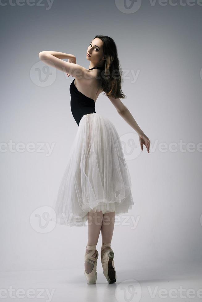 a ballerina in a bodysuit and a white skirt improvises classical and modern choreography in a photo studio