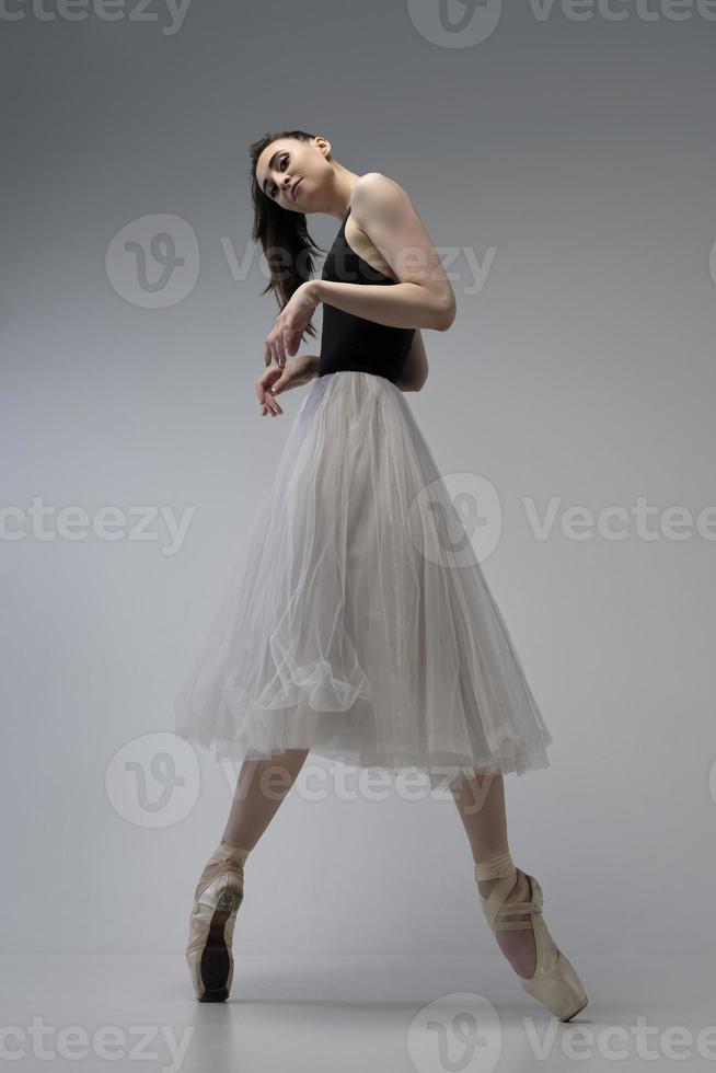 ballerina in a bodysuit and a white skirt improvises classical and modern choreography in a photo studio