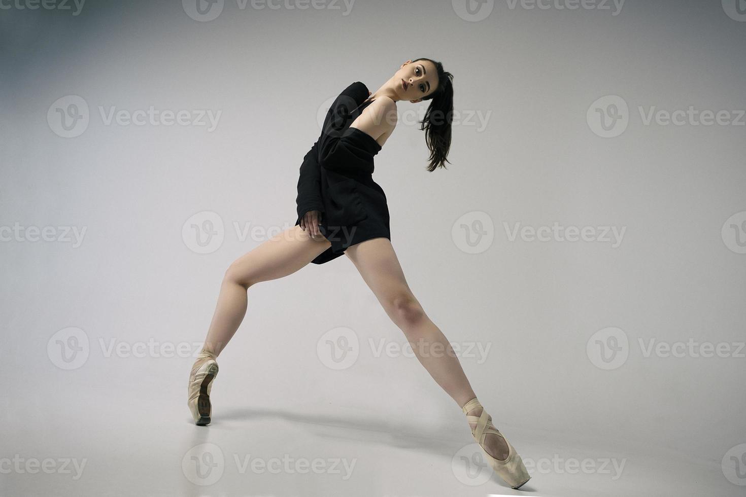 ballerina in a bodysuit and a black jacket improvises classical and modern choreography in a photo studio