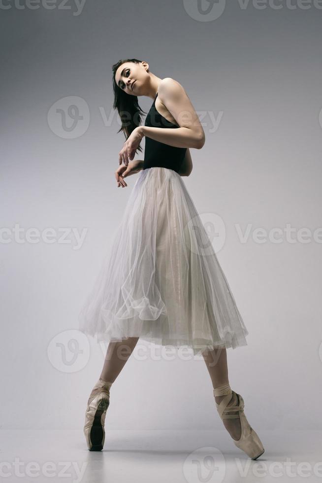 a ballerina in a bodysuit and a white skirt improvises classical and modern choreography in a photo studio