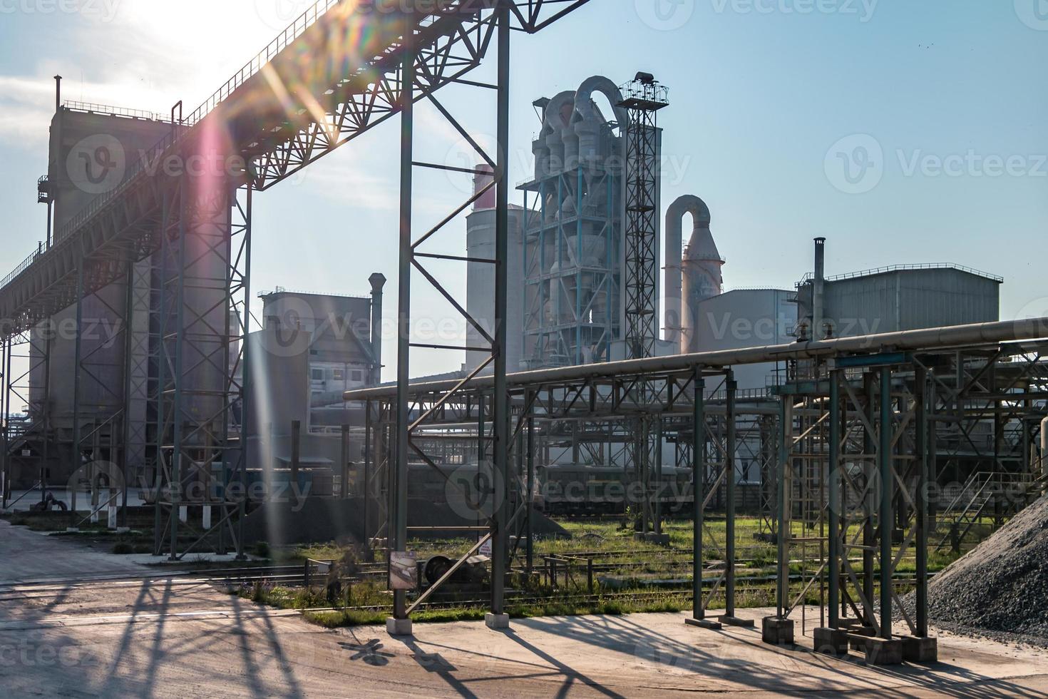 Industrial grey landscape environmental pollution waste of cement factory. Big pipes of industry enterprise plant. mountains of sand and rubble photo