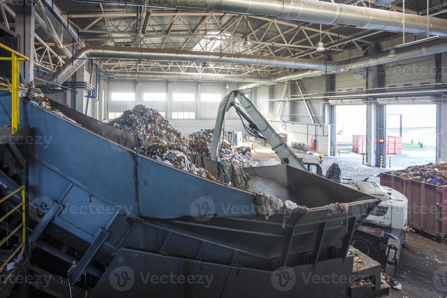 excavadora en la clasificación primaria de basura en la planta de procesamiento de residuos. recolección de basura por separado. reciclaje y almacenamiento de residuos para su posterior eliminación. foto